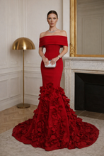 Woman in a red off-shoulder gown with floral details in an elegant room.

The La Roseraie Gown is an exquisite expression of modern couture and timeless femininity. Designed to sculpt and flatter, this off-the-shoulder mermaid silhouette elegantly frames the neckline while contouring the waist and hips for a refined, elongated look.

Crafted with a structured bodice and smooth, body-skimming fabrication, the gown flows effortlessly into a dramatic floor-length train adorned with hand-placed three-dimensiona