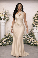 Woman in a beige evening gown standing in front of floral decorations.

Luxury model wearing a one-shoulder satin gown with gold waist detail, styled for an elegant formal setting with refined floral backdrop.