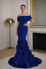Woman wearing a blue off-shoulder gown with floral details in an elegant room.

The La Roseraie Gown is an exquisite expression of modern couture and timeless femininity. Designed to sculpt and flatter, this off-the-shoulder mermaid silhouette elegantly frames the neckline while contouring the waist and hips for a refined, elongated look.

Crafted with a structured bodice and smooth, body-skimming fabrication, the gown flows effortlessly into a dramatic floor-length train adorned with hand-placed three-dime