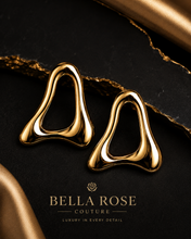 Luxury gold statement earrings with sculptural open design displayed on an elegant black background with gold accents