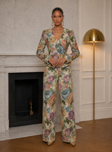 Woman wearing a floral jumpsuit in a room with a fireplace and gold lamp.