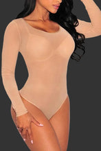 Beige bodysuit worn by a model on a black background